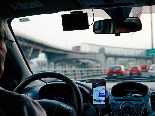 A driver sitting in a car in traffic while using GPS navigation on a smartphone