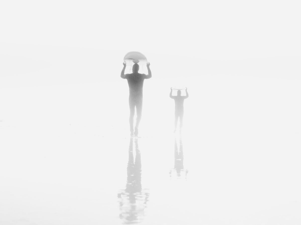 people carrying surfboards through the fog