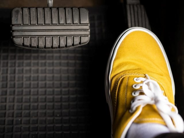 A man in yellow sneakers steps on the accelerator of a car, representing accelerating adoption of AI-Driven Personalization.