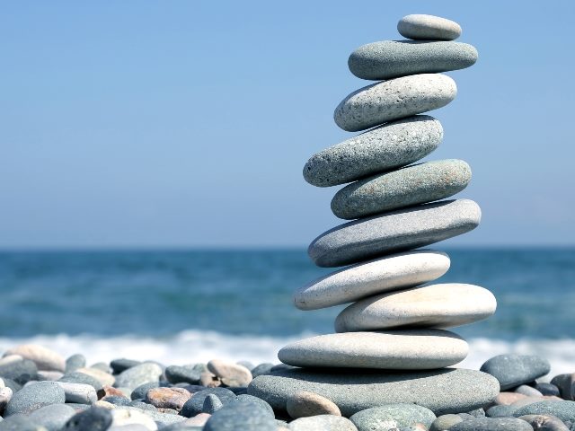 A stack of smooth stones on the seashore with the ocean in the background. 
