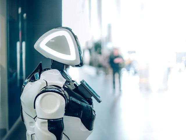 A smart robot assistant with artificial intelligence in public place. People are blurred in the background.