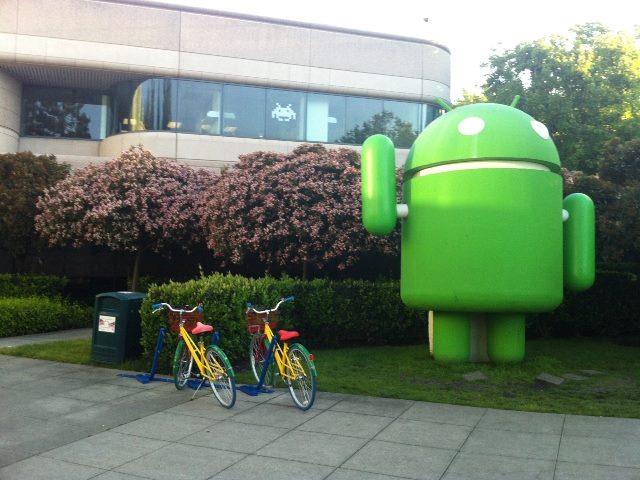 Google android Mountainview Californai building with tow bikes in Google primary colors and lime green bot in front.