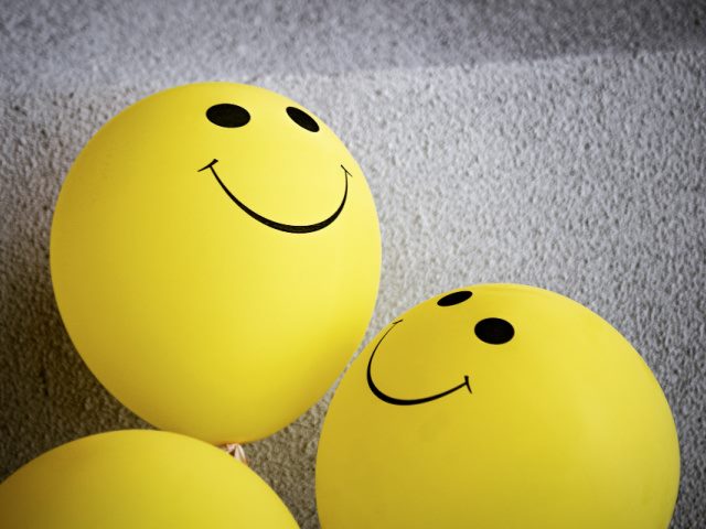 yellow balloons with a smiley face design in front of a gray background