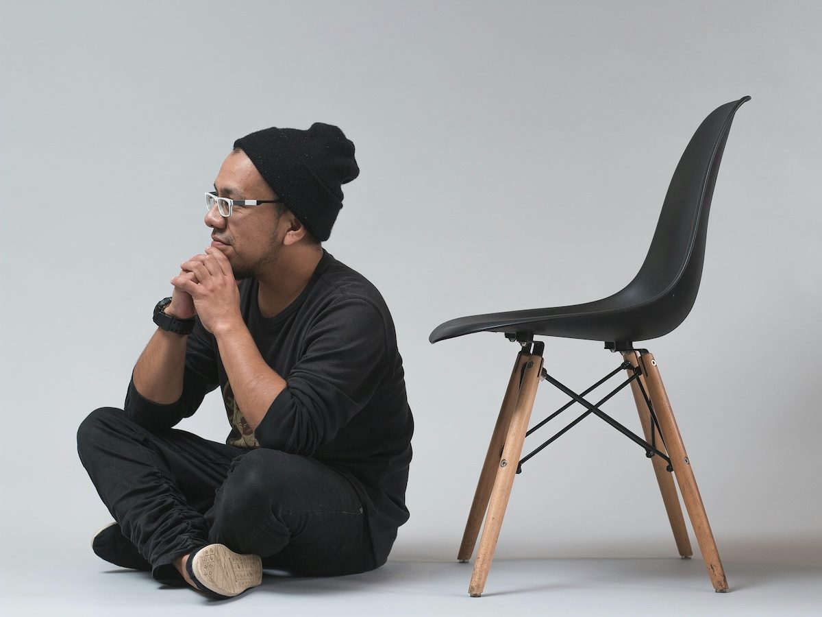 a person sitting on the floor thinking. an empty chair behind them