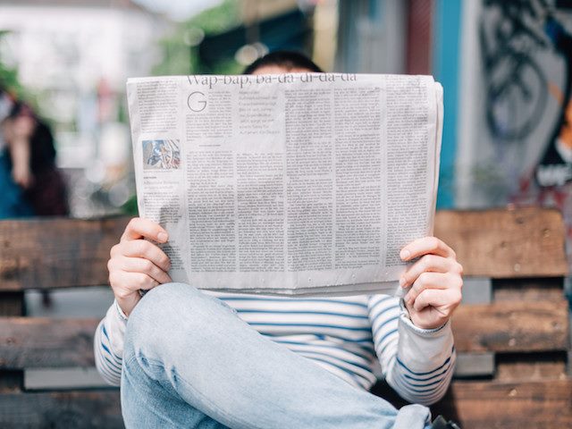man on bench reading a newspaper
