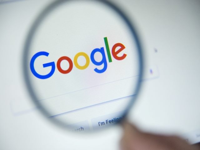 Google's homepage on the screen under a magnifying glass.