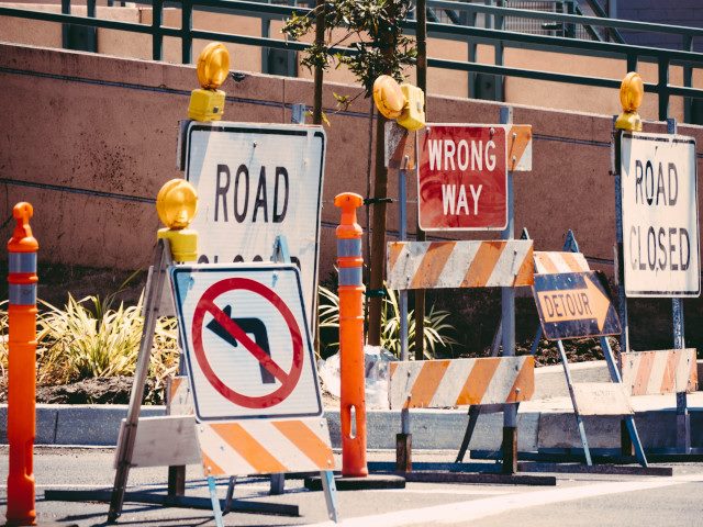 A group of road closed signs stand across a road.