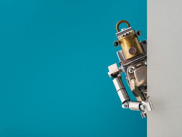 A steampunk robot peeks around a gray wall with a turquoise blue background.
