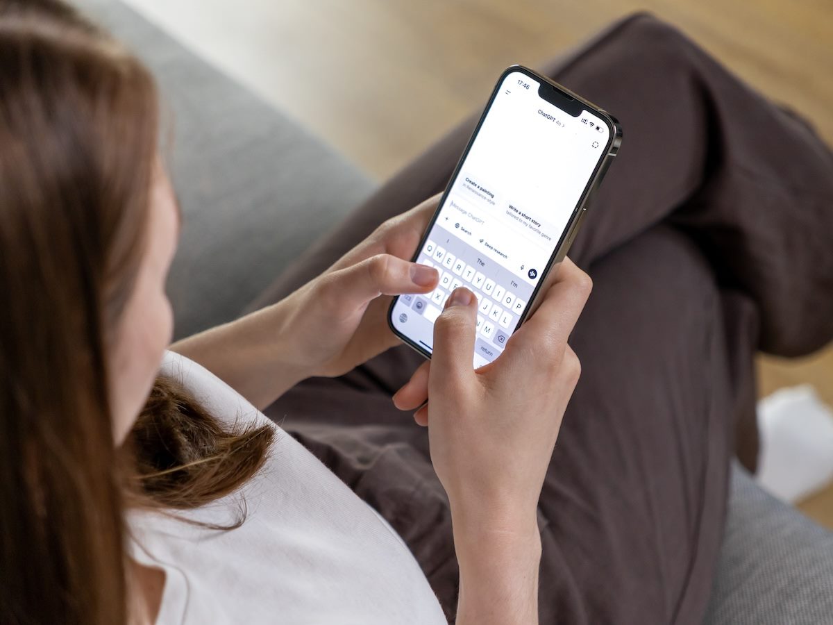 Woman holding smartphone and typing message to ChatGPT