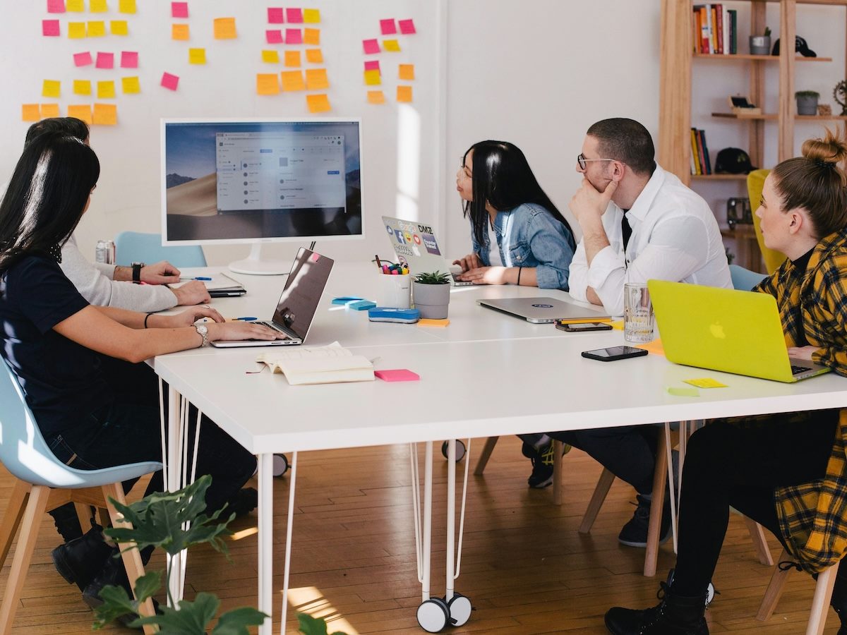 team of five people gathered together at a table, problem solving