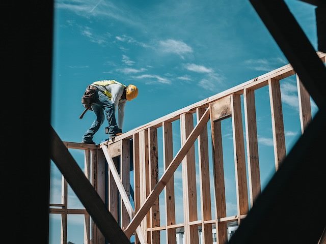 Man scaling foundation of building in hard hat