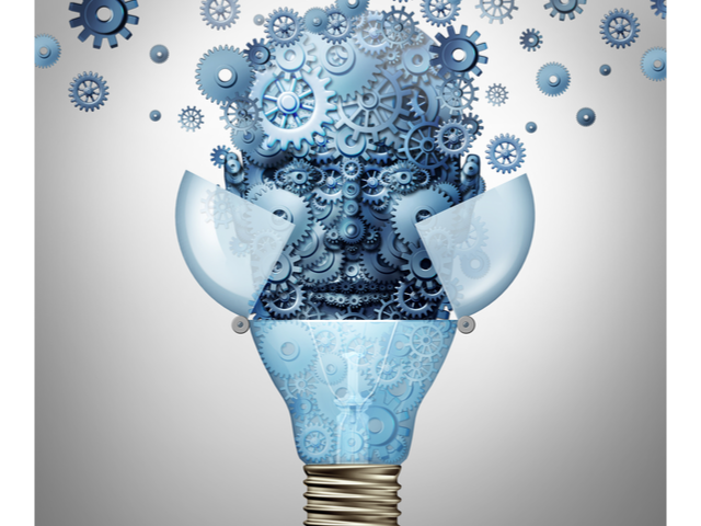 Artificial intelligence ideas as a robot head symbol made of gears and cog wheels emerges out of an open light bulb