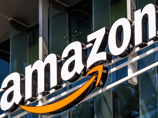 Amazon name in white lettering and yellow curved arrow logo on side of glass and steel building.