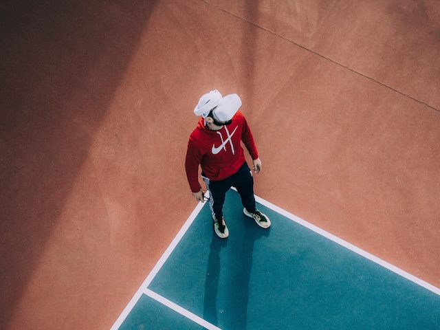 man wearing a virtual reality headset standing on the edge of a tennis court