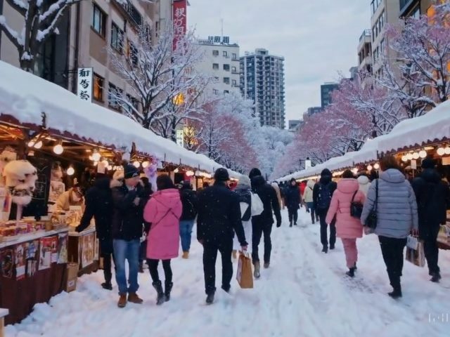 Scene at a Japanese winter market of people walking in the snow surrounded by outdoor vendors, a screenshot of a video created by OpenAI Sora.