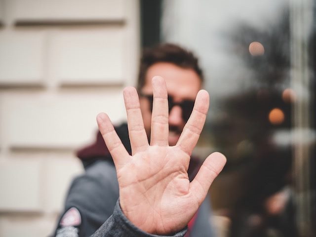 man holding up his hand with five fingers extended