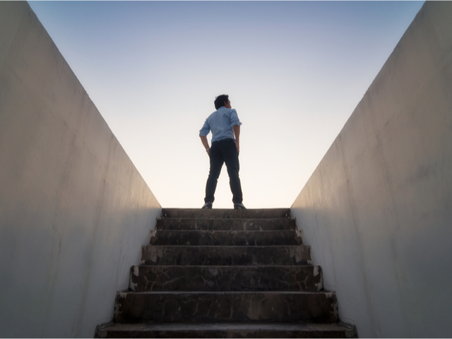 A businessman standing at the top of the stairwell in the sunshine - scaling up strategy concept