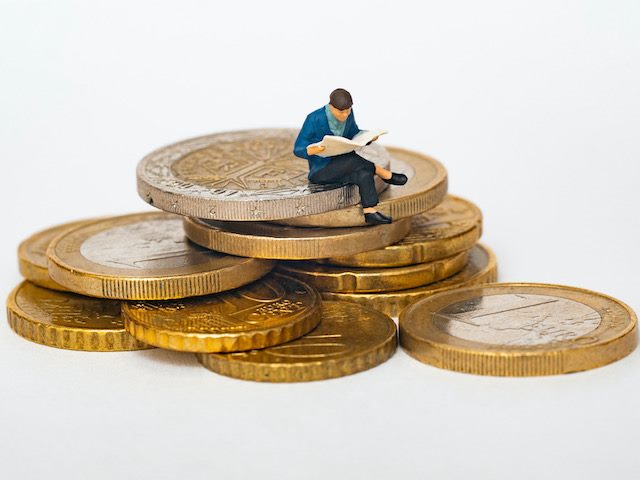 figurine sitting on a pile of euro coins