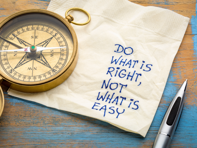 A pocket compass sitting on a napkin with a handwritten note on it. The note says do what is right not what is easy