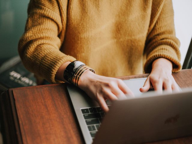 An employee works on a laptop computer on a desk.