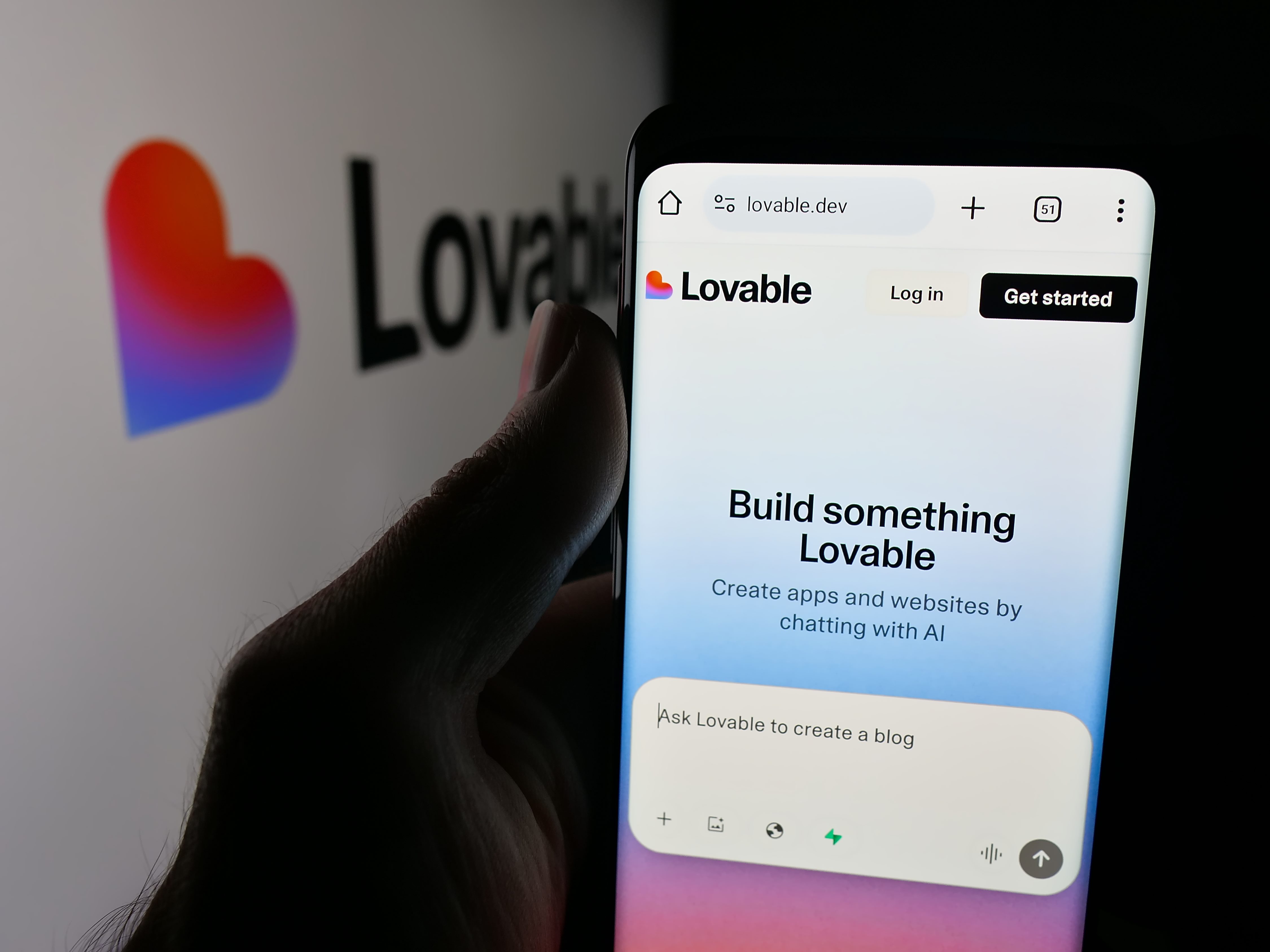 Person holding smartphone with web page of Swedish ai software company Lovable Labs Inc. on screen in front of logo
