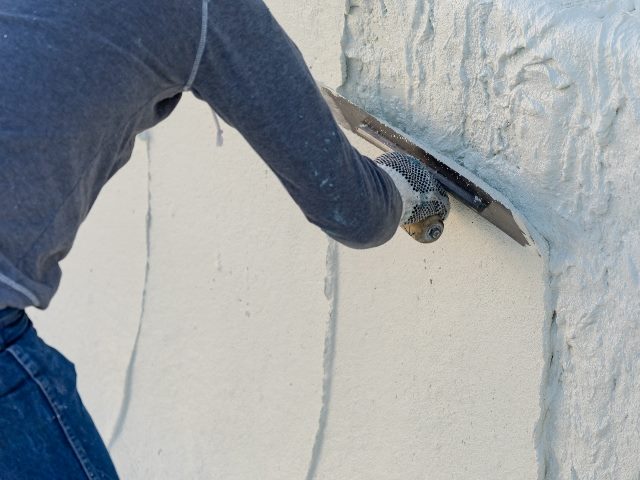 A man wearing bluejeans and a blue shirt smooths wet plaster on a wall with a trowel, suggesting how generative AI in marketing can smooth operations. 