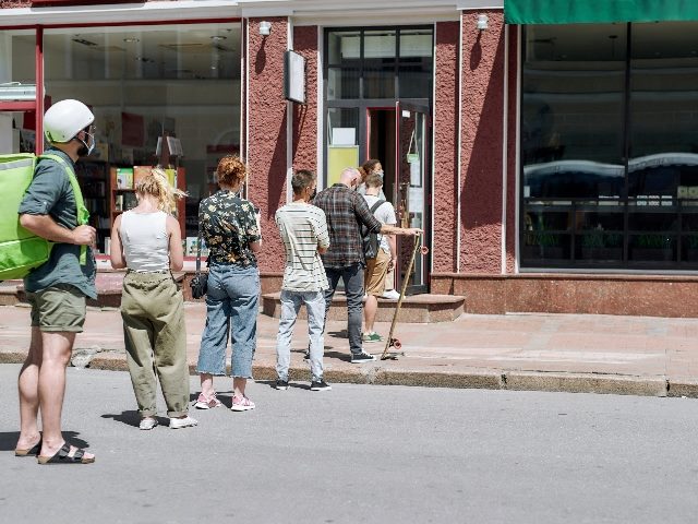 Full length shot of people waiting, standing in line, respecting social distancing to collect their order. 