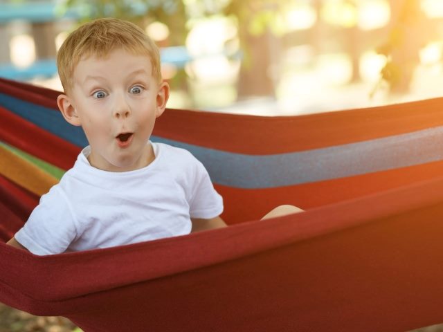 A boy sits in a hammock with a delighted look, symbolizing a delighted customer emotions.