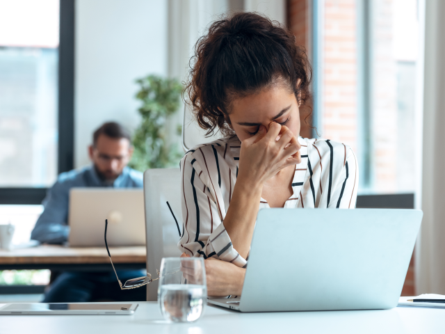 Tired business woman with headache looking uncomfortable while working with computer - creepy marketing concept