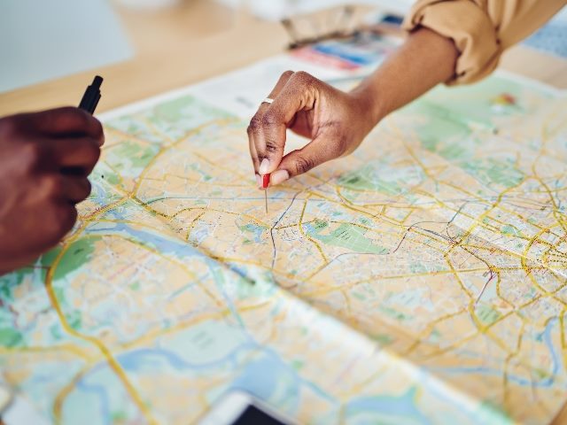 Cropped image of women's hands pointing on mark on cartography planning adventure. 