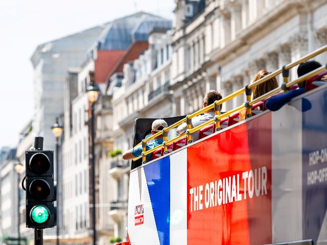 Haymarket street with sign exterior on bus for the original tour double decker bus in summer with people riding by green signal.