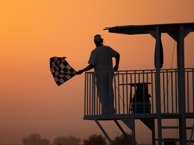 A man holding the finish flag at a race, representing AI "winning" over the call center