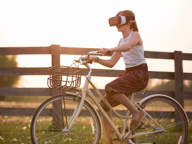 woman riding a bicycle with VR goggles on
