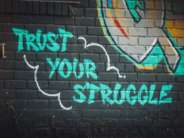 graffiti on the wall reading: "trust your struggle"