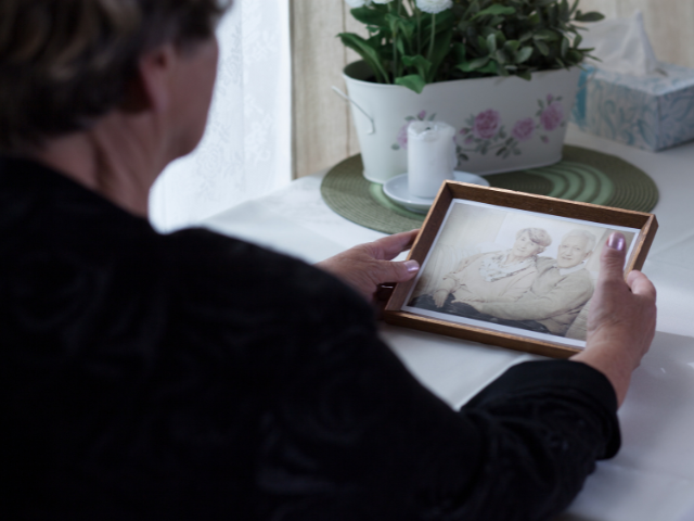 A person sitting and looking at a framed photograph 
