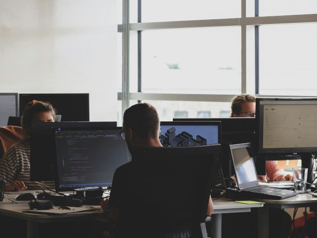A group of software engineers work on computers at an office.