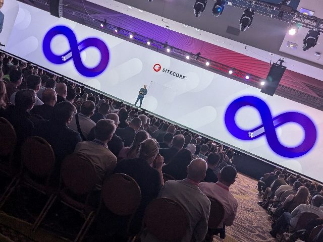 Shot of Sitecore CEO Dave O'Flanagan on stage during his Sitecore Symposium keynote, with attendees sitting in the crowd in front of him.
