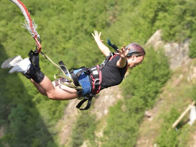 A woman bungee jumps with a look of fear on her face as she plunges downward,  symbolizing the the need for marketers to embrace AI in content marketing.