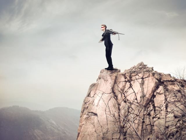 A businessman with a winged rocket strapped on his back, while standing at the edge of the cliff - cx experimentation concept