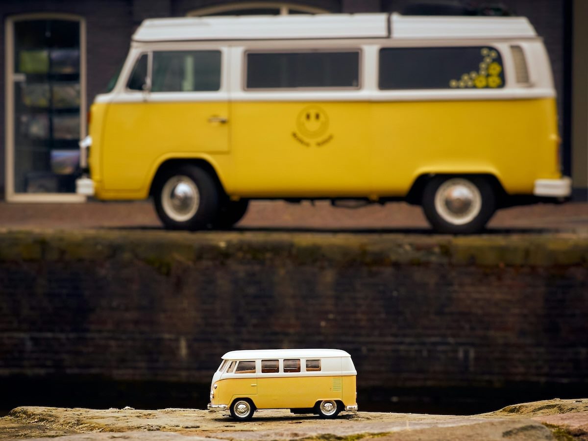 a model Volkswagen bus in the foreground, a real Volkswagen bus in the background
