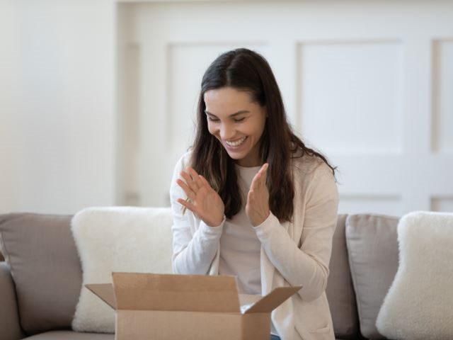 A woman looking into a recently opened package, with excitement - customer loyalty concept