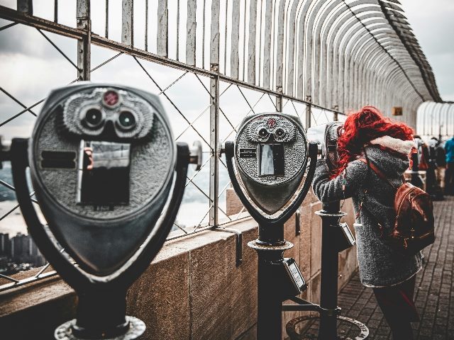 A woman searches uses a coin-operated binocular next to some unused ones.