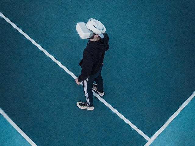 man standing in tennis court with virtual reality goggles on