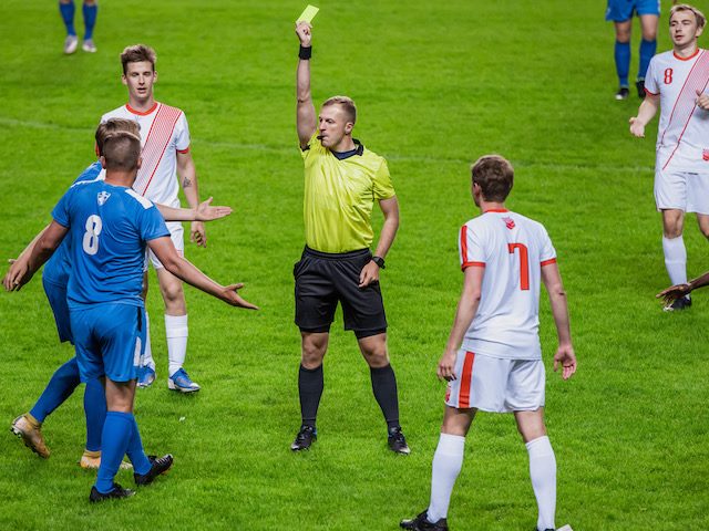 referee giving a yellow card in the middle of a soccer match