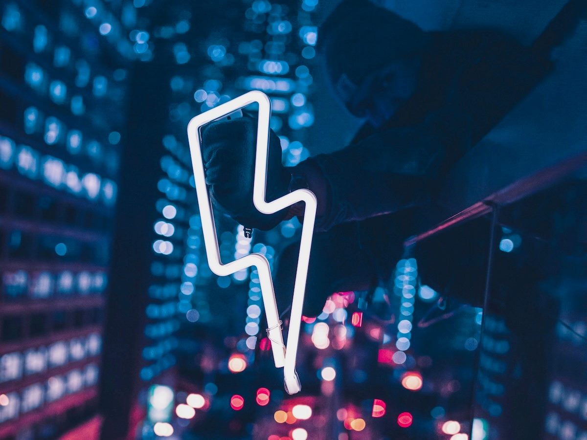 neon lightning bolt sign being held up against the night sky