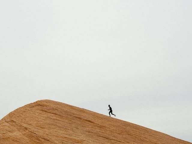 man in silhouette running to the horizon