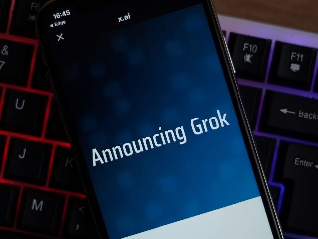 The words "Announcing Grok" appear on a smart phone over top a computer keyboard in news piece about Elon Musk's new AI chatbot. 