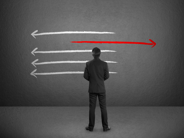 Businessman drawing several arrows in same direction with the exception of one arrow pointing the other way. - AI in the mainstream concept