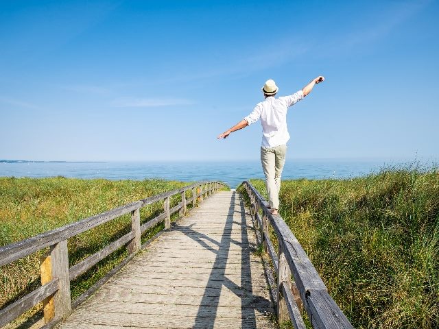  Young man walking on a rail on a beach boardwalk.