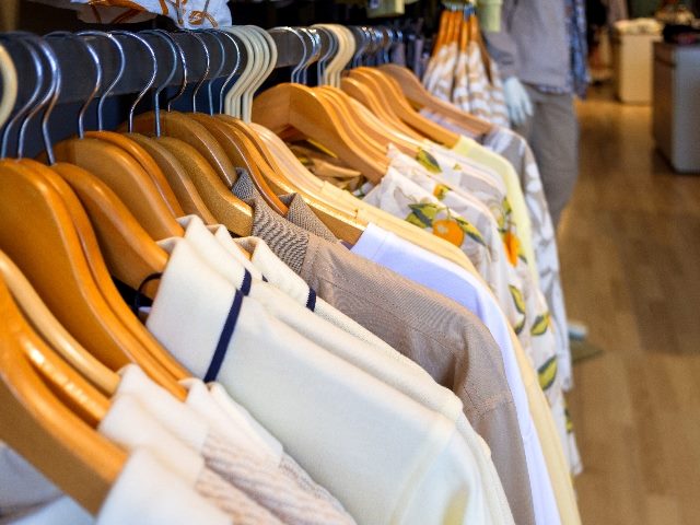  Close-up of clothes neatly arranged on wooden hangers in a clothing store. 